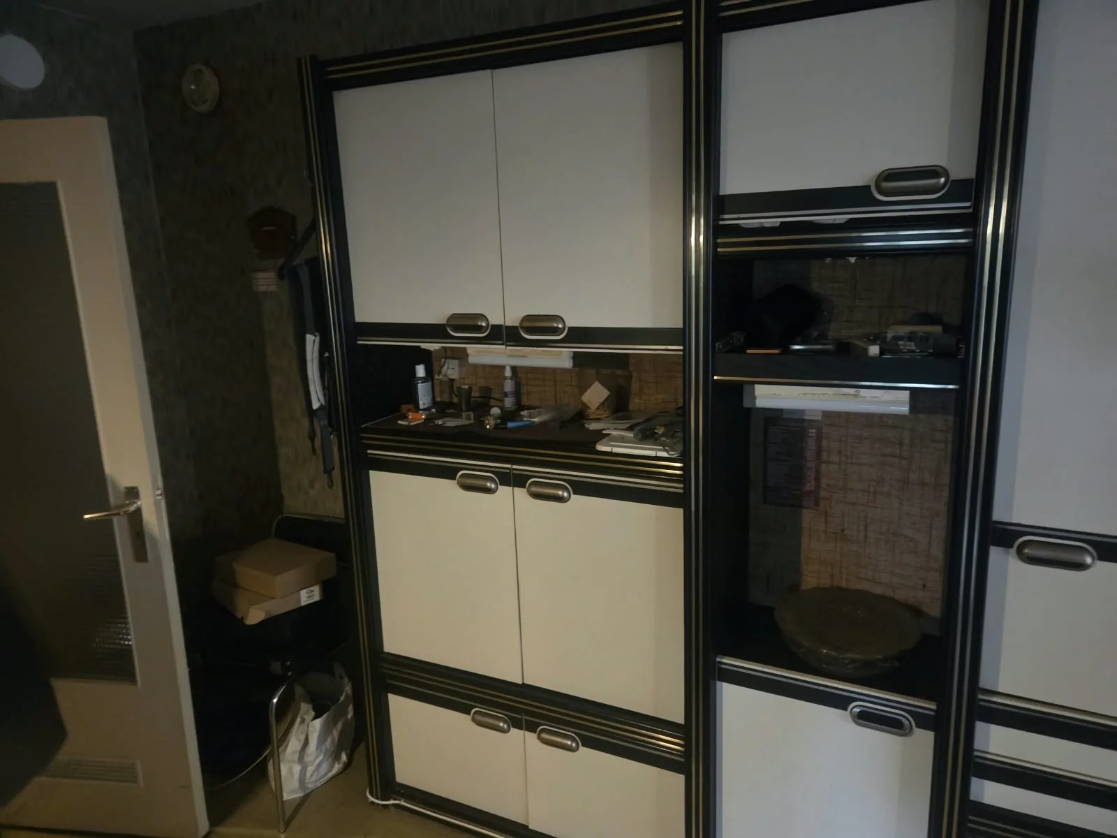 Appartement leegmaken: zwart-witte kastenwand met kleine spullen op het werkblad