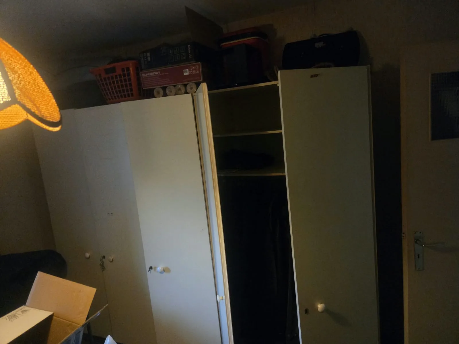 Appartement leegmaken: witte kleerkast met dozen en manden erop